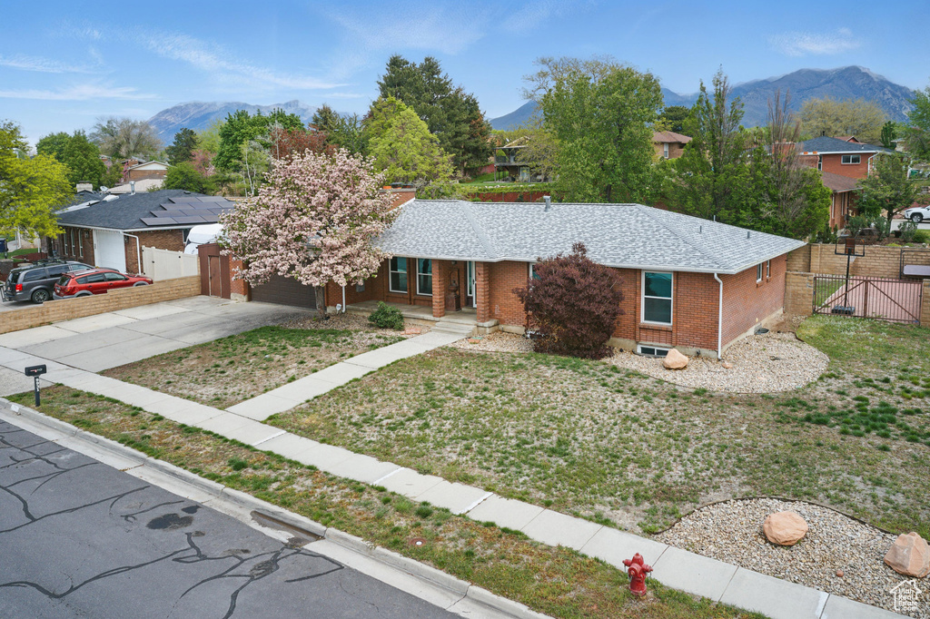 Ranch-style home with a gate, a mountain view, brick siding, driveway, and a porch