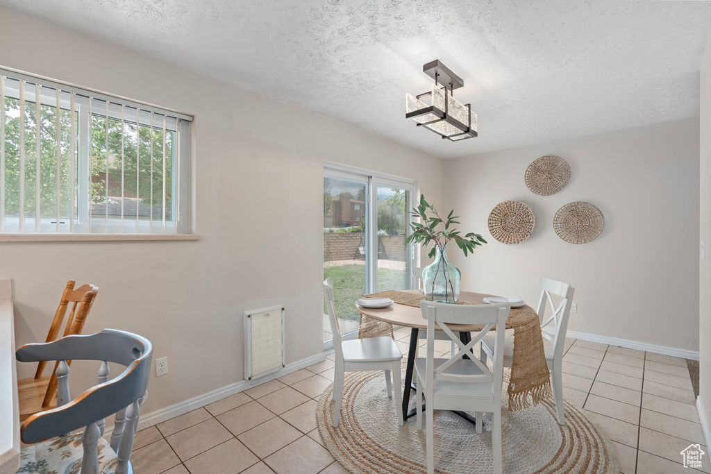 Dining area featuring plenty of natural light, light tile patterned floors, a textured ceiling, and baseboards