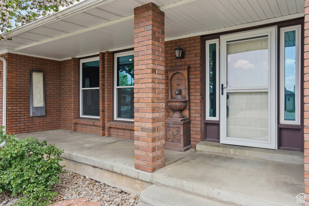 Entrance to property featuring brick siding and covered porch