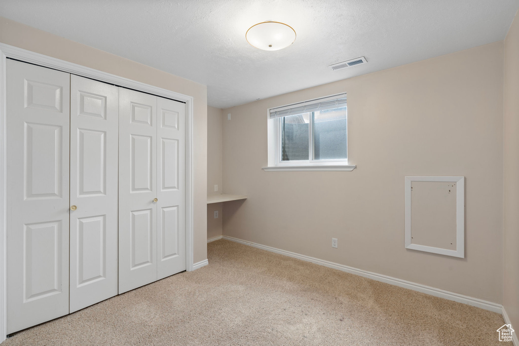 Unfurnished bedroom with carpet, a closet, and baseboards