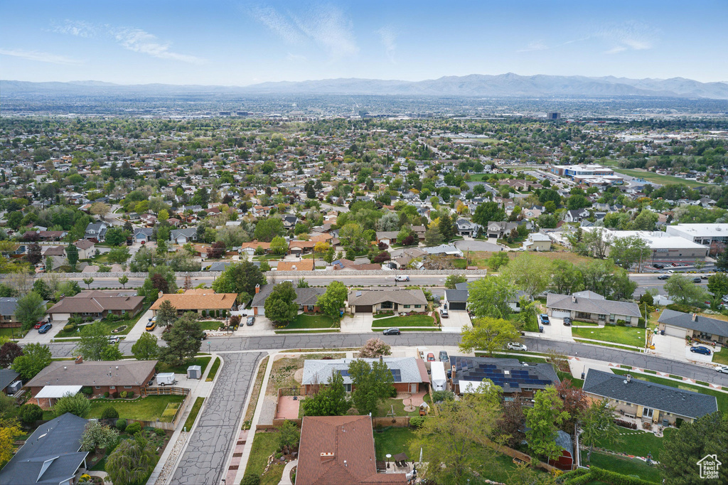 Aerial view of property and surrounding area featuring mountains and nearby suburban area