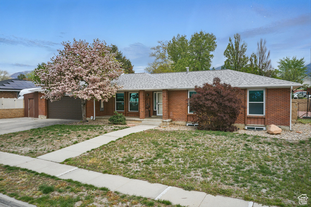 Ranch-style home with an attached garage, concrete driveway, brick siding, and a shingled roof