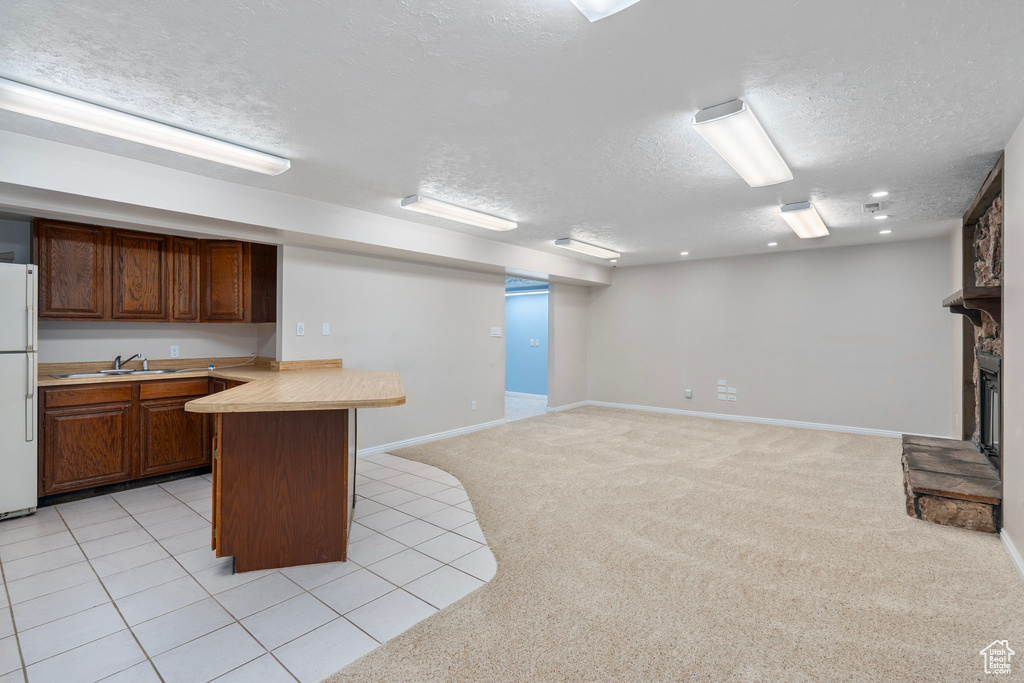 Kitchen with a textured ceiling, a sink, light countertops, freestanding refrigerator, and light carpet