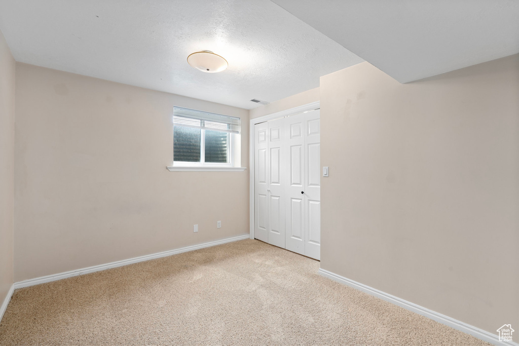 Unfurnished bedroom featuring baseboards, carpet floors, a closet, and a textured ceiling