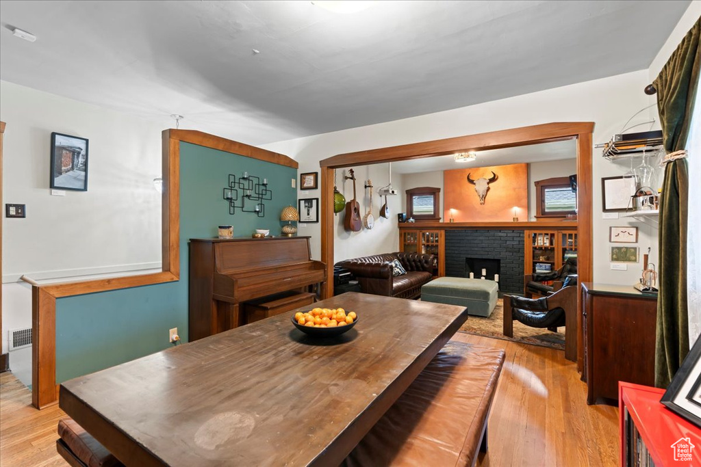 Dining area with light wood-style floors and a brick fireplace