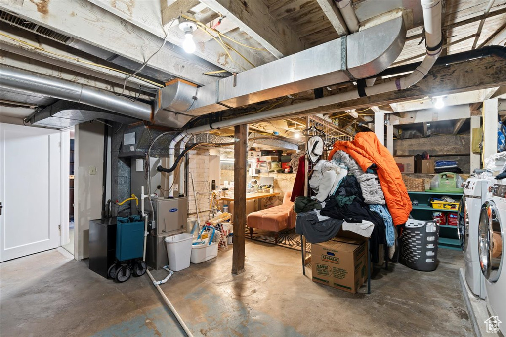 Unfinished below grade area with heating unit, visible vents, and washer and dryer