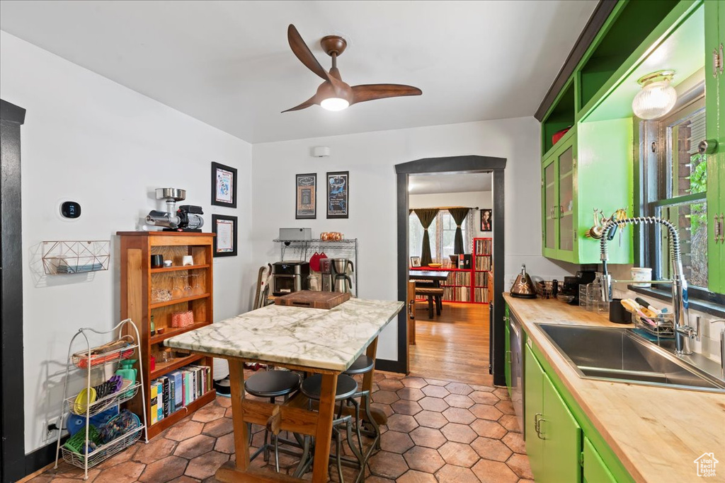 Kitchen with a ceiling fan, a sink, tile patterned floors, green cabinets, and butcher block countertops