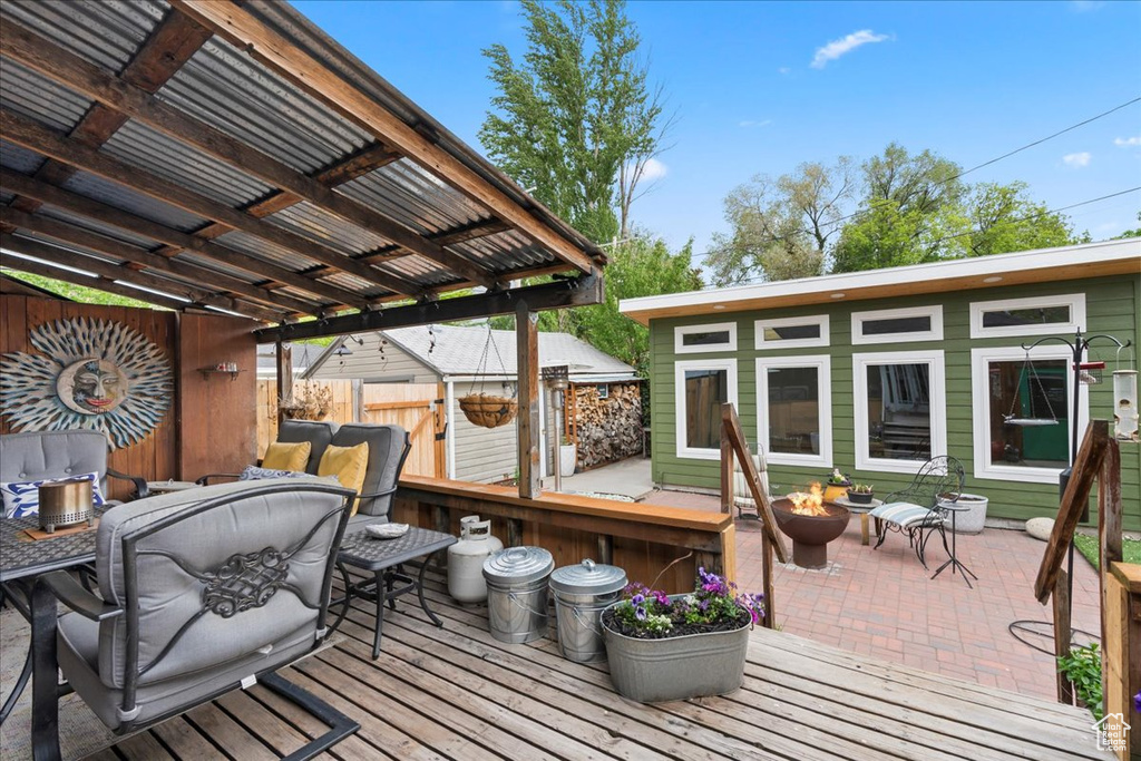 Deck with an outdoor fire pit, a patio, outdoor dining area, and fence