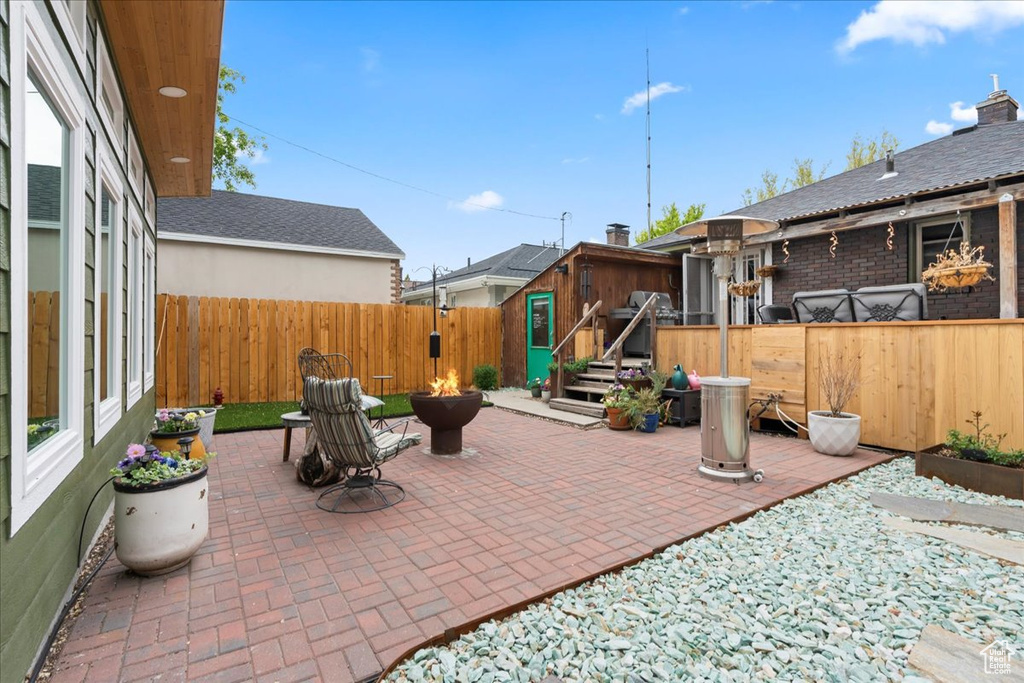 View of patio with an outdoor fire pit, an outbuilding, and a fenced backyard