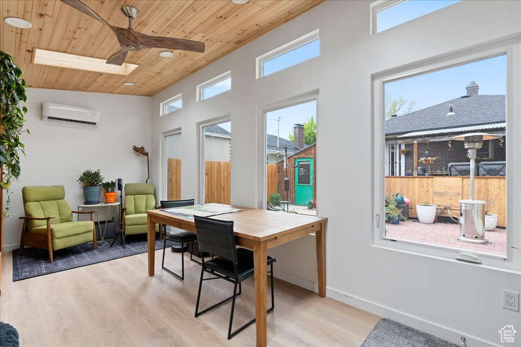 Office space with a skylight, wood ceiling, a wall unit AC, and plenty of natural light