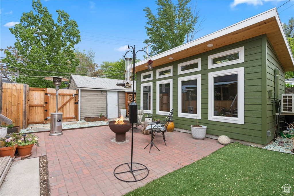 Rear view of house featuring fence, an outdoor structure, an outdoor fire pit, a patio area, and a gate