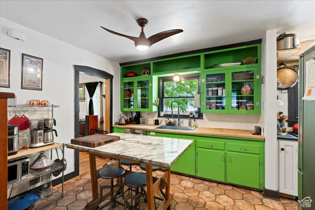 Kitchen with light tile patterned floors, stainless steel dishwasher, ceiling fan, and a sink