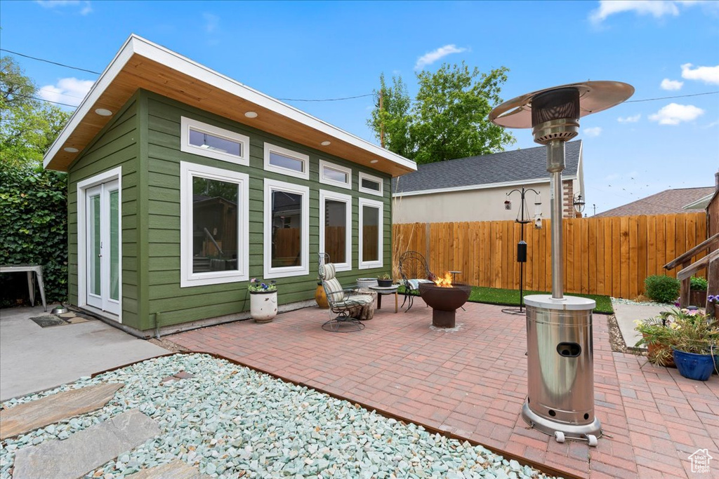 View of patio featuring an outbuilding, a fire pit, and fence