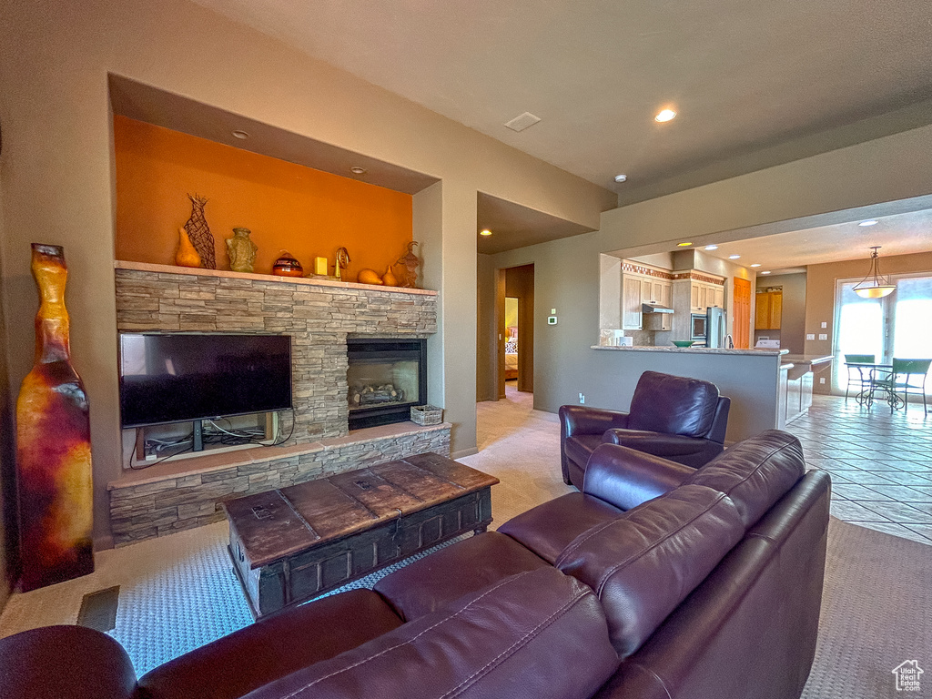 Living area featuring light tile patterned floors, light carpet, a stone fireplace, and recessed lighting