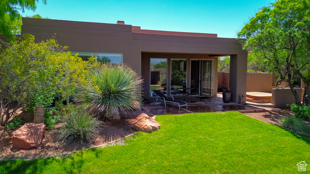 Back of property featuring a yard, stucco siding, and a patio area