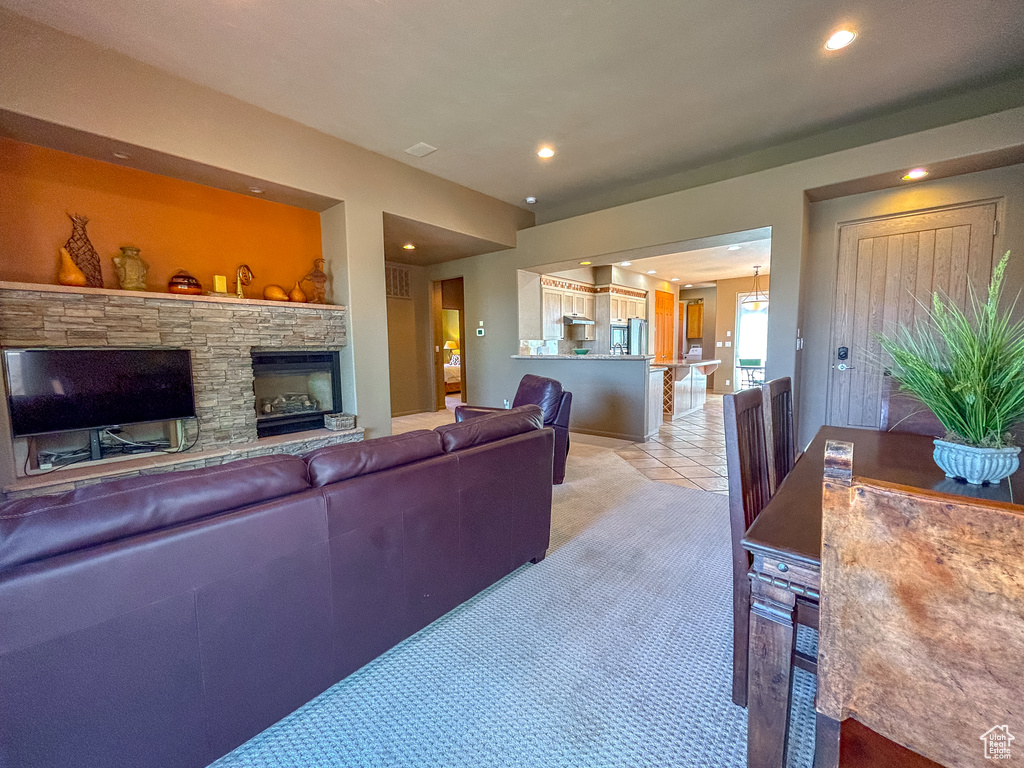 Living area with a fireplace, light colored carpet, light tile patterned floors, and recessed lighting