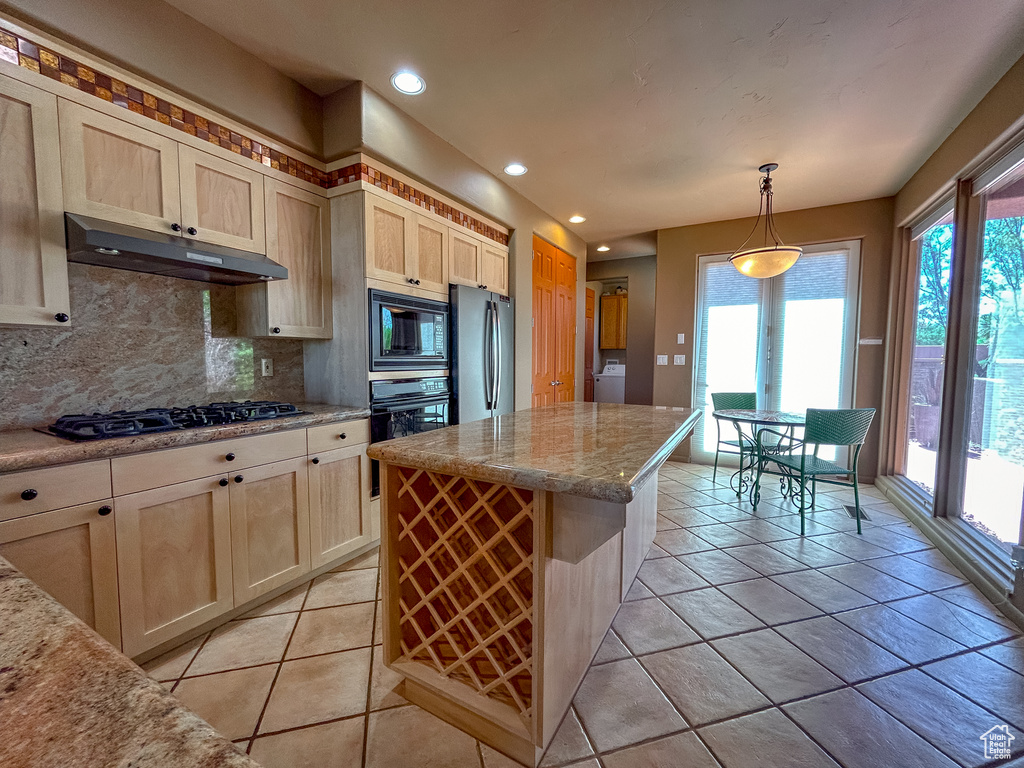 Kitchen with washer / clothes dryer, tasteful backsplash, black appliances, under cabinet range hood, and plenty of natural light