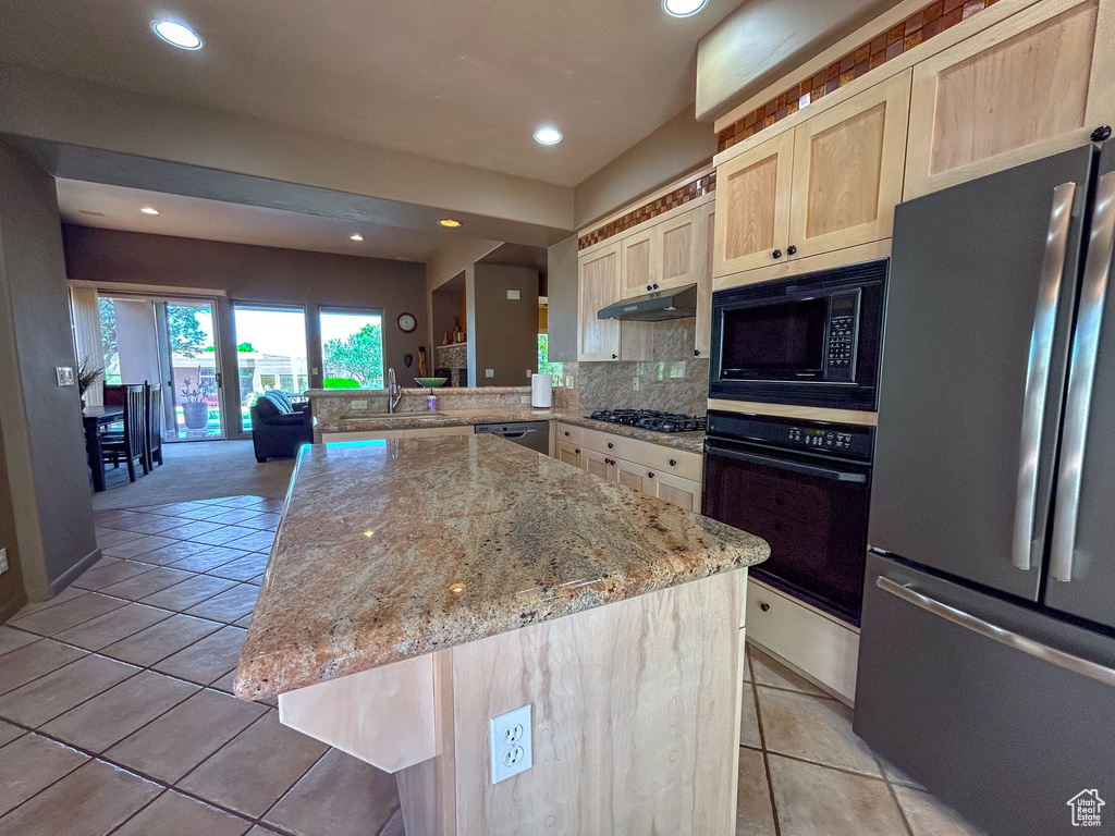 Kitchen featuring light tile patterned floors, light stone counters, black appliances, and light brown cabinetry