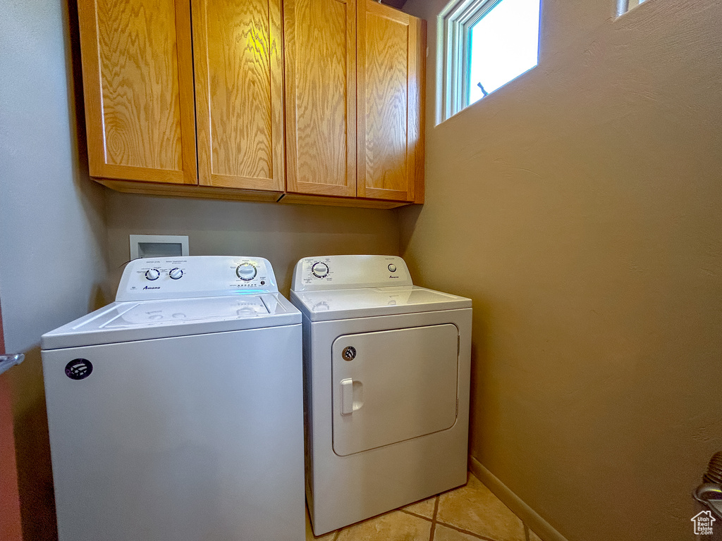 Washroom with cabinet space, washing machine and dryer, and light tile patterned floors