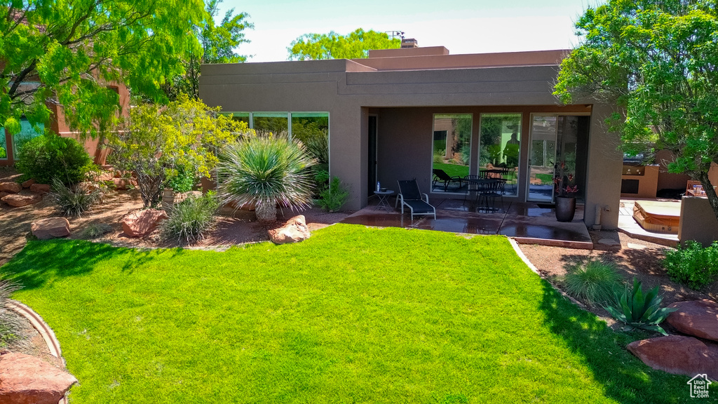 Back of property with stucco siding, a chimney, a lawn, and a patio area
