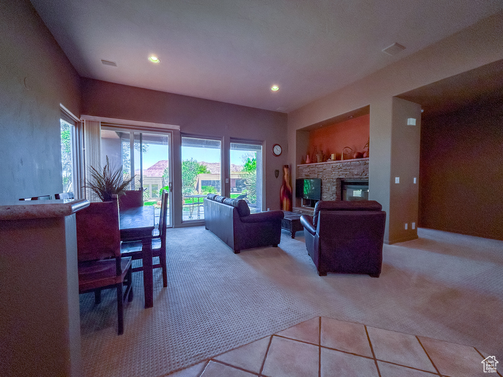 Living area featuring a stone fireplace, light carpet, visible vents, and recessed lighting