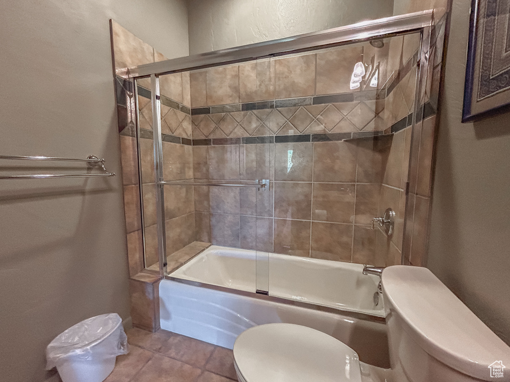 Full bath featuring toilet, shower / bath combination with glass door, and tile patterned floors