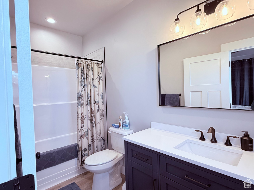Full bathroom with vanity, shower / bath combination with curtain, and toilet