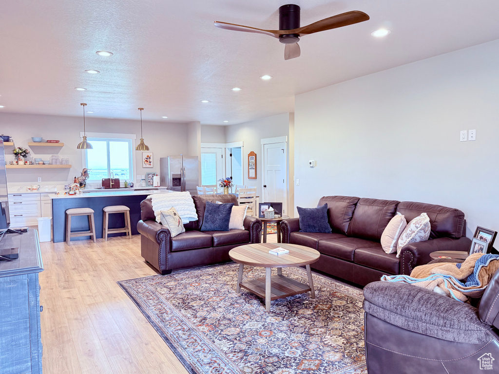 Living room featuring recessed lighting, ceiling fan, and light wood-style flooring