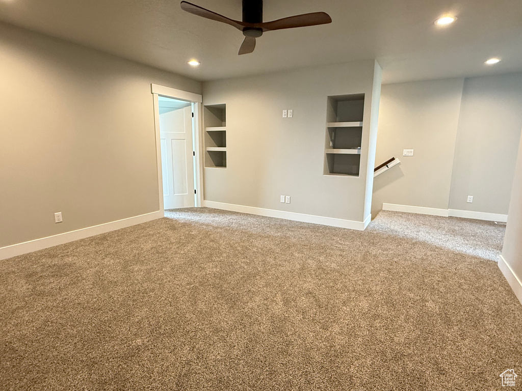 Unfurnished living room featuring a ceiling fan, recessed lighting, carpet floors, baseboards, and built in shelves