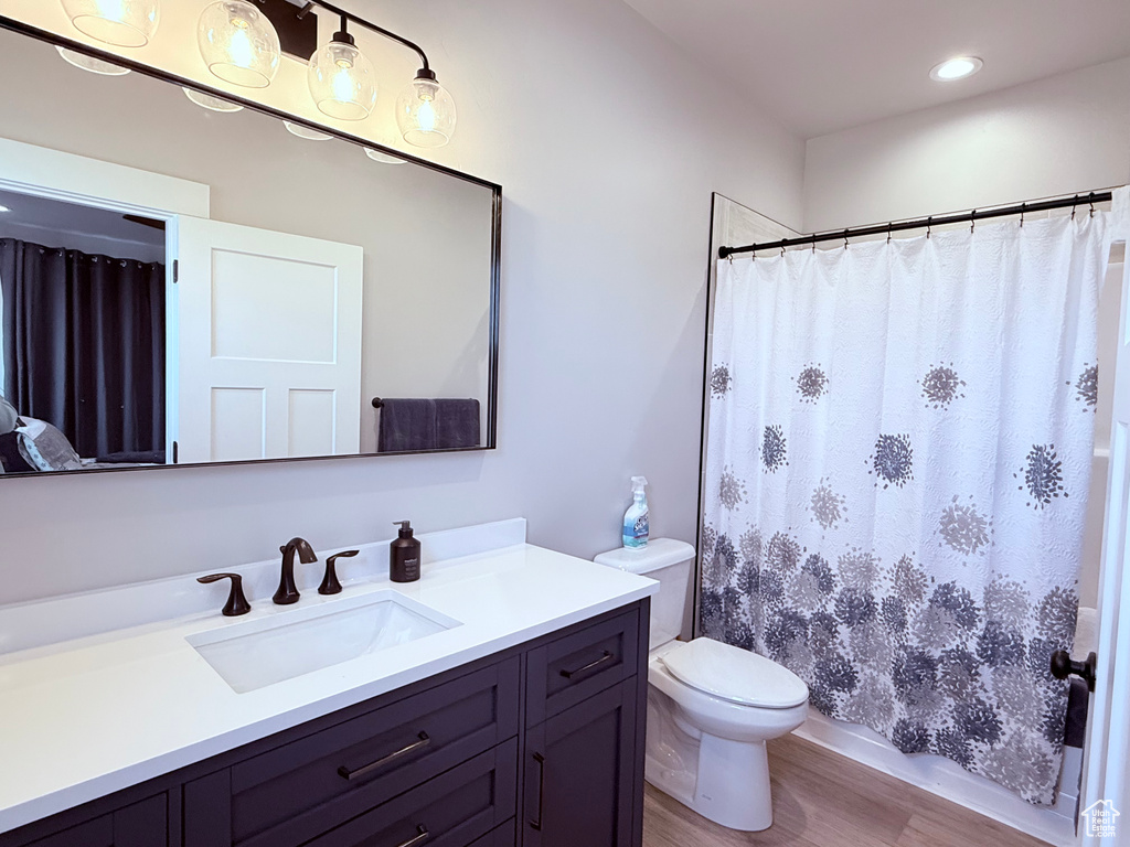 Full bath featuring wood finished floors, toilet, vanity, a shower with curtain, and recessed lighting
