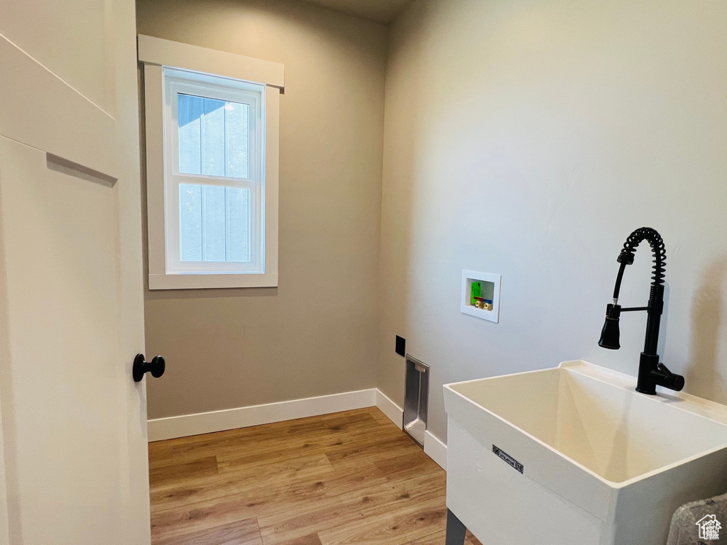 Washroom with washer hookup, light wood-type flooring, and baseboards