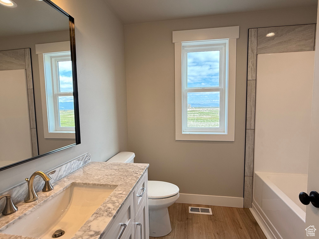 Bathroom with wood finished floors, baseboards, toilet, vanity, and recessed lighting