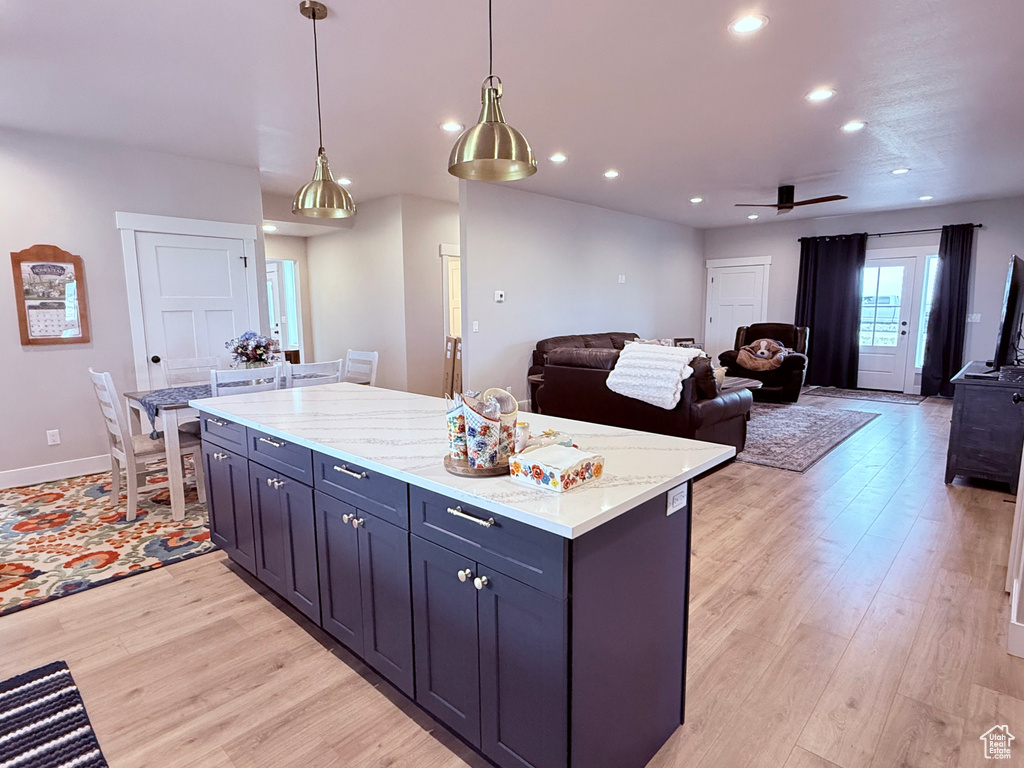 Kitchen featuring light wood finished floors, ceiling fan, recessed lighting, a kitchen island, and pendant lighting