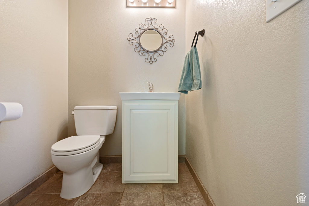 Bathroom with toilet, tile patterned flooring, baseboards, and a sink