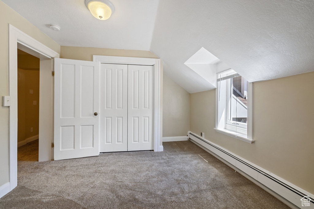 Additional living space featuring baseboard heating, carpet, lofted ceiling, and baseboards