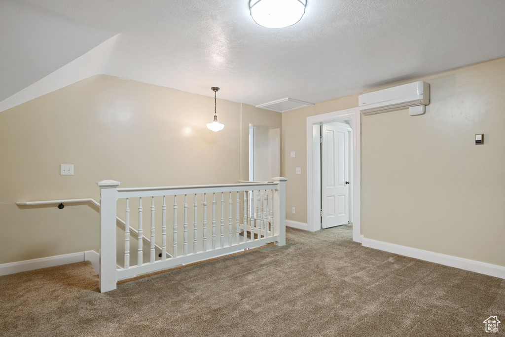 Empty room featuring a wall mounted AC, carpet, and baseboards