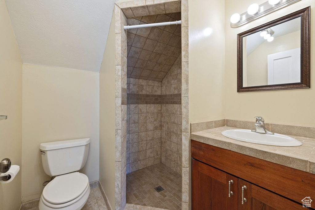 Full bathroom with a tile shower, toilet, vanity, and tile patterned flooring