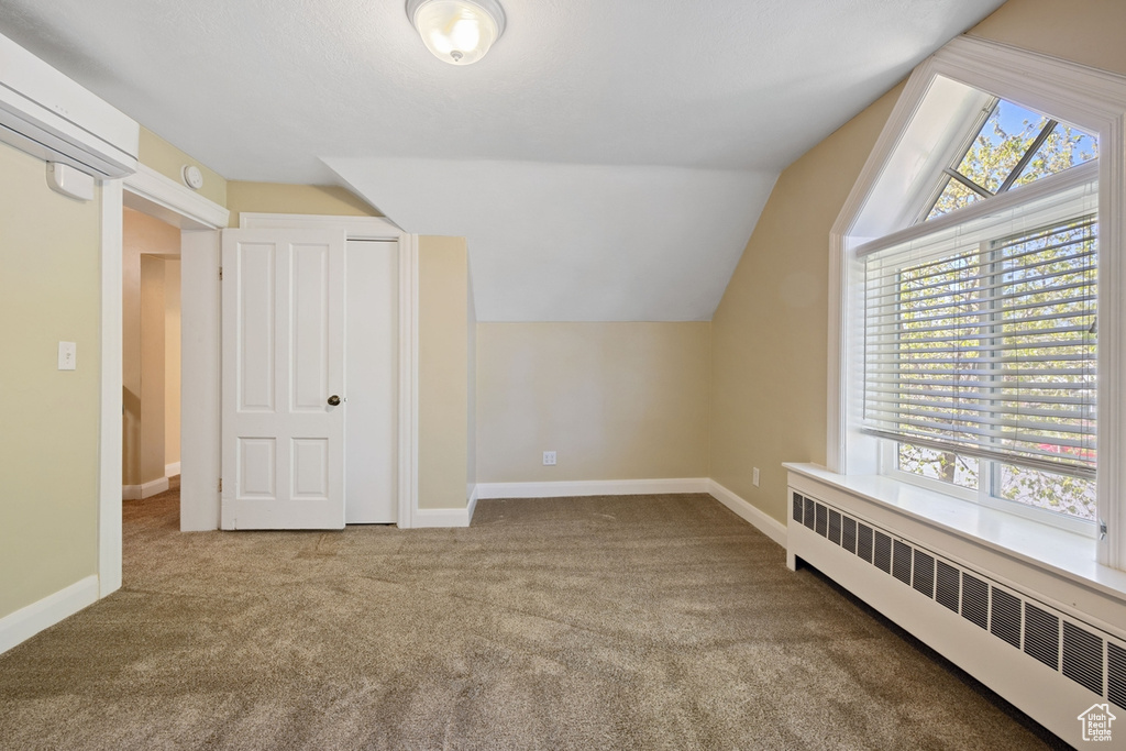 Bonus room with carpet flooring, vaulted ceiling, baseboards, radiator, and a baseboard heating unit