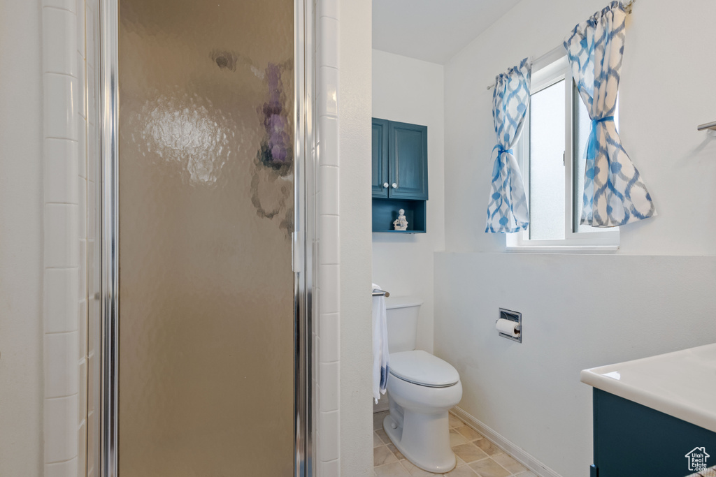 Full bath with toilet, a stall shower, vanity, and baseboards