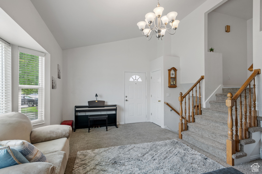 Carpeted living room with a chandelier, stairway, and high vaulted ceiling