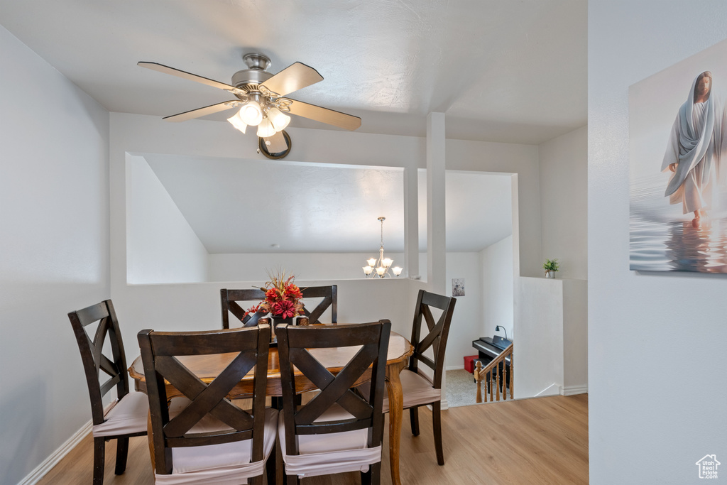 Dining area with light wood finished floors, a chandelier, a ceiling fan, and baseboards