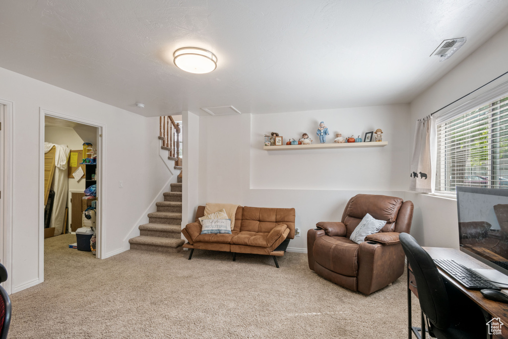 Living area featuring light carpet, stairs, and baseboards