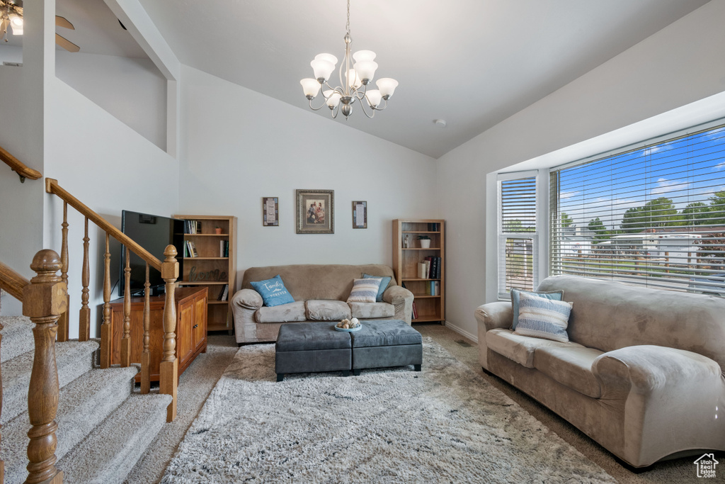 Living room with carpet floors, a chandelier, lofted ceiling, stairs, and baseboards