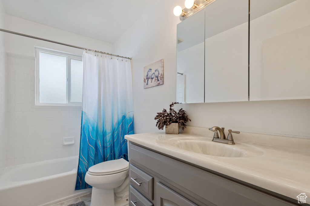Bathroom featuring vanity, toilet, and shower / bath combination with curtain