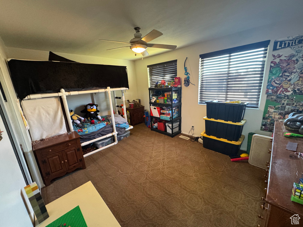 Carpeted bedroom with a ceiling fan and baseboards