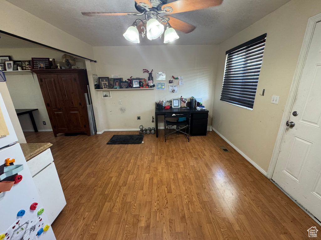 Office space featuring a ceiling fan, light wood-style flooring, and baseboards