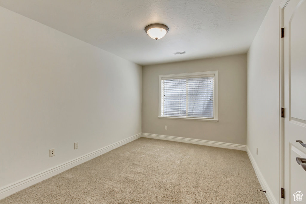 Empty room with light colored carpet and baseboards