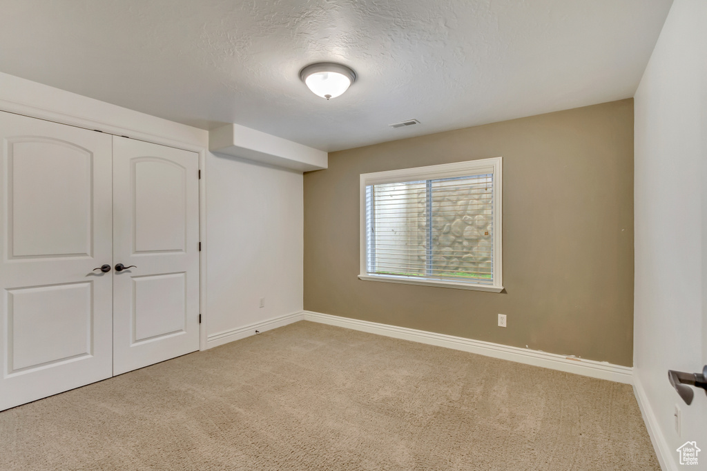 Unfurnished bedroom with carpet, baseboards, a textured ceiling, and a closet