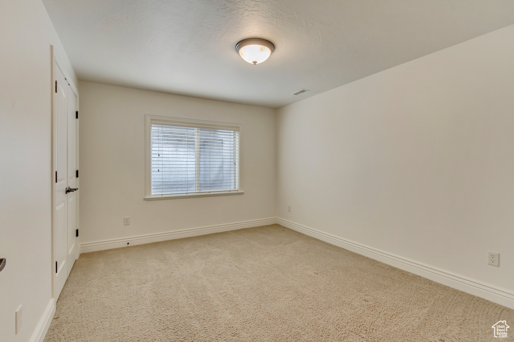 Spare room featuring light carpet and baseboards