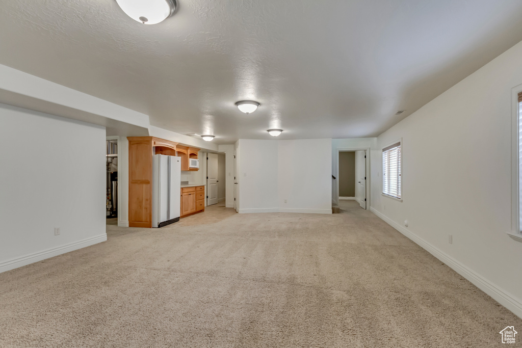 Unfurnished living room with light carpet and baseboards